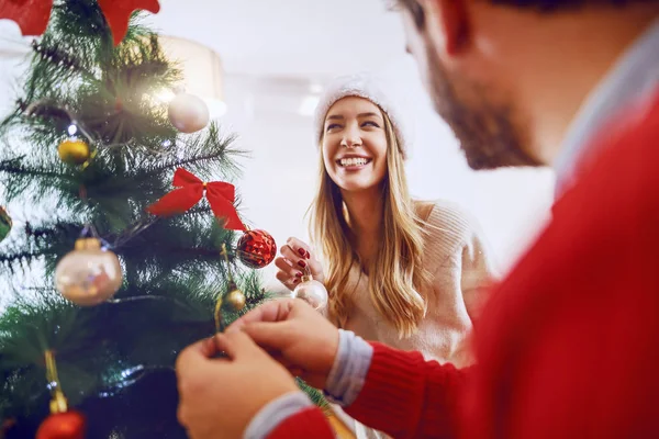 可爱的白人夫妇装饰着圣诞树 两个头上都戴着桑塔帽 客厅内部 — 图库照片