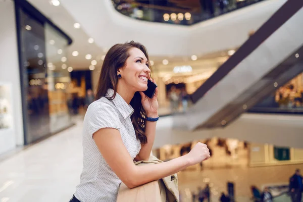 Ohromující Usměvavá Bruneta Která Opírá Zábradlí Mluvení Telefonu Interiér Nákupního — Stock fotografie