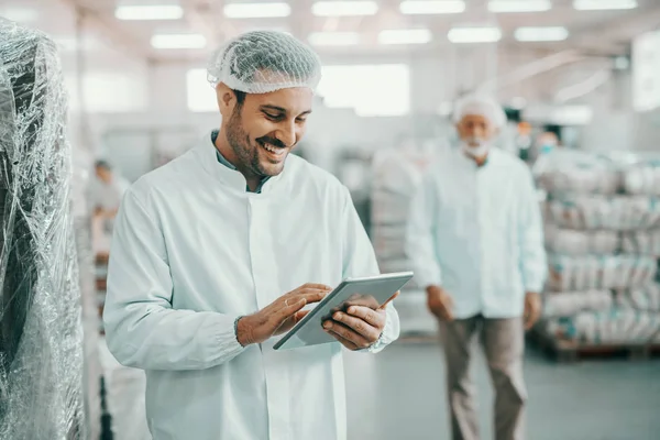 Steril Üniformalı Gülümseyen Kafkasyalı Yönetici Elinde Tabletle Gıda Fabrikasında Duruyor — Stok fotoğraf