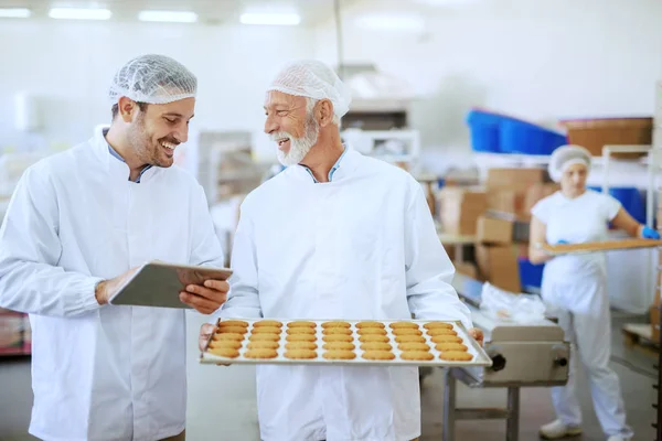 Vassoio Anziani Adulti Con Biscotti Freschi Mentre Supervisore Valuta Qualità — Foto Stock