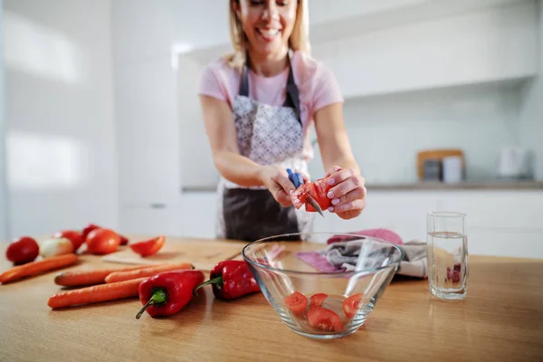 Sorrindo Atraente Mulher Loira Caucasiana Digna Avental Corte Tomate Enquanto — Fotografia de Stock