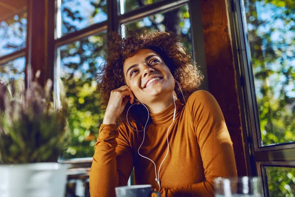 Portret Atrakcyjnej Uśmiechniętej Mieszanki Młodej Kobiety Siedzącej Kawiarni Słuchającej Muzyki — Zdjęcie stockowe