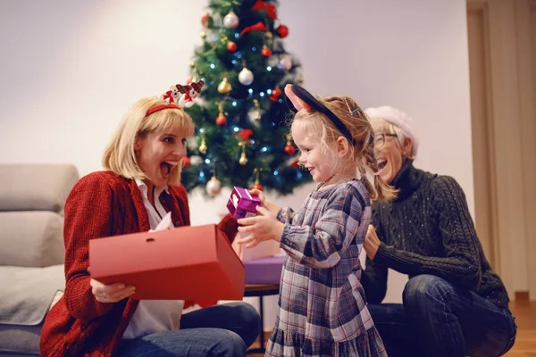 Verblüffte Junge Mutter Mit Weihnachtsgeschenk Von Ihrer Liebenden Tochter Hintergrund — Stockfoto