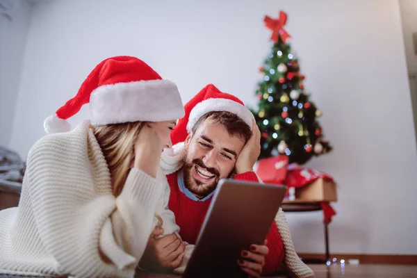 Kafalarında Noel Baba Şapkasıyla Yerde Yatan Mesaj Göndermek Için Tablet — Stok fotoğraf