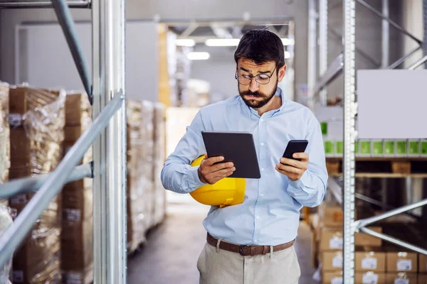 Jovem Bonito Empregado Barbudo Segurando Tablet Telefone Inteligente Nas Mãos — Fotografia de Stock