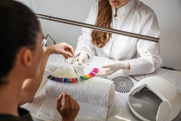 Estetista Seduto Tavola Mostrando Una Donna Colori Campioni Smalto Salone — Foto Stock