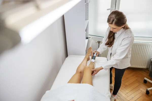 美容师在女性腿上使用蜡去除毛发 美容院内部 — 图库照片