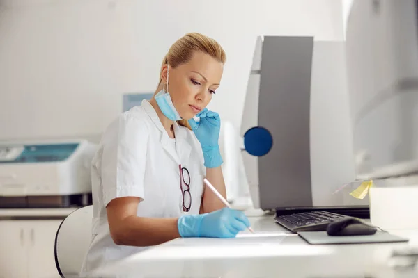 Jovem Loira Dedicada Assistente Laboratório Feminino Sentado Anotando Resultados Dos — Fotografia de Stock