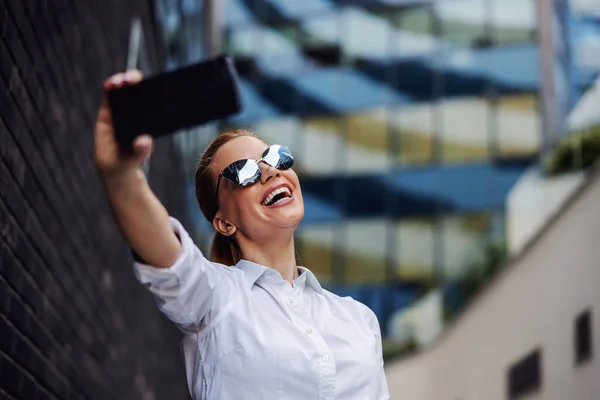 Uśmiechnięta Piękna Modna Bizneswoman Okularach Przeciwsłonecznych Stojąca Zewnątrz Robiąca Selfie — Zdjęcie stockowe