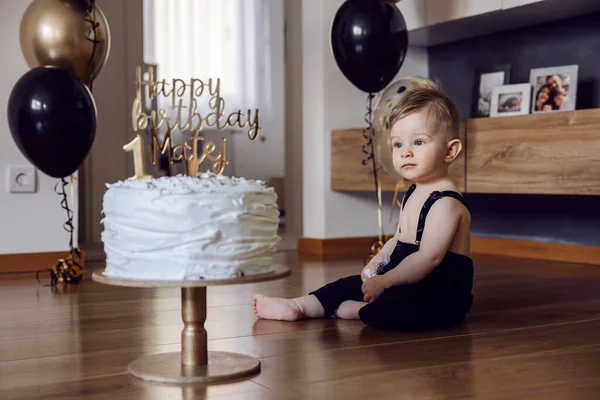 かわいい赤ちゃんの男の子が床に座って 彼の最初の誕生日にケーキを見て — ストック写真