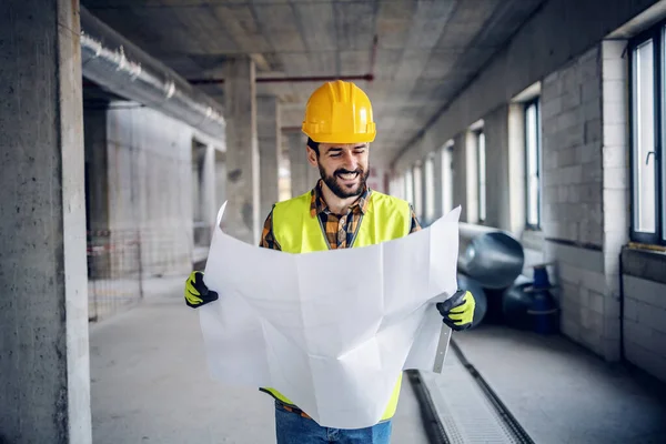 在施工过程中 穿着工作服 头戴头盔 努力工作 努力工作的建筑工人的微笑 看图纸 — 图库照片