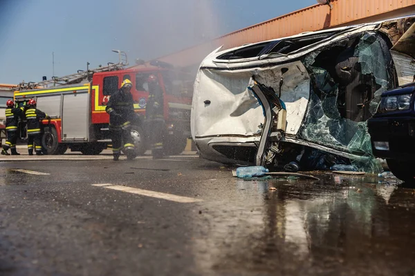 Πυροσβέστες Δράση Πυροσβέστες Σβήνουν Φωτιά Και Προσπαθούν Ανατρέψουν Τρακαρισμένο Αυτοκίνητο — Φωτογραφία Αρχείου