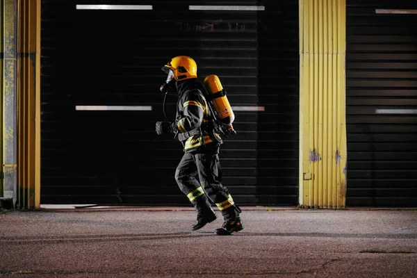 炎の世話をするために実行されている完全な機器と保護制服の勇敢な消防士 — ストック写真