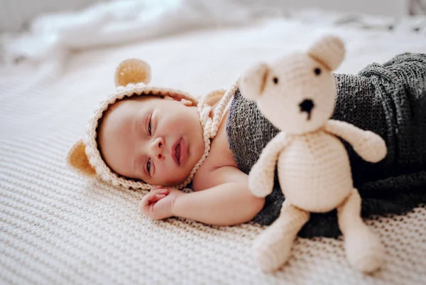 美しい新生児のサイドビューウールのスカーフで包まれ 頭の上にキャップがおもちゃの横に眠っています — ストック写真