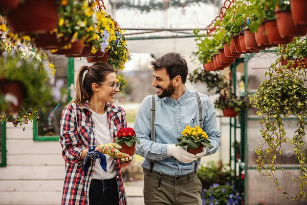 Dos Trabajadoras Jardín Heterosexuales Sonrientes Sosteniendo Macetas Con Flores Caminando —  Fotos de Stock