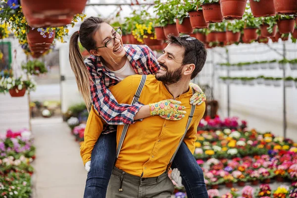 若いですカップルで愛を持っていますPiggybackで温室 — ストック写真