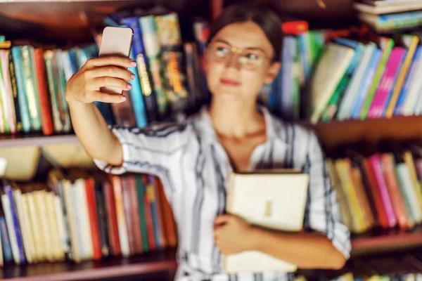 Joven Guapa Morena Vestido Con Anteojos Sosteniendo Libro Tomando Selfie — Foto de Stock
