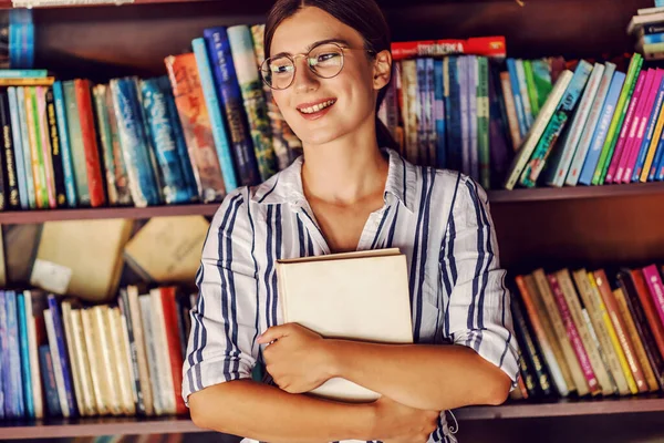 Młoda Atrakcyjna Studentka Sukience Stojąca Bibliotece Przed Półkami Książkami Trzymająca — Zdjęcie stockowe