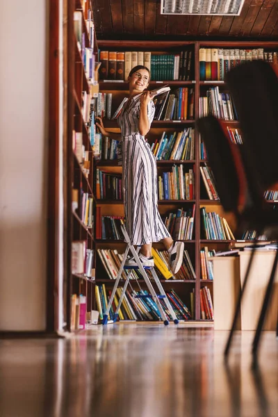 Pleine Longueur Jeune Bibliothécaire Attrayant Debout Sur Échelle Tenant Livre — Photo