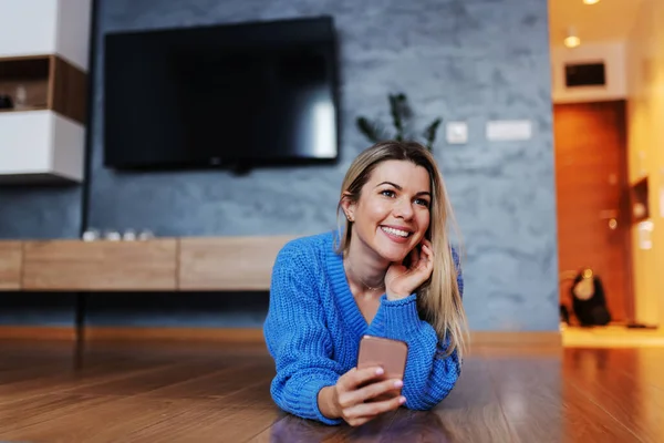 Atraktivní Usměvavá Blondýnka Ležící Břiše Obývacím Pokoji Pomocí Chytrého Telefonu — Stock fotografie