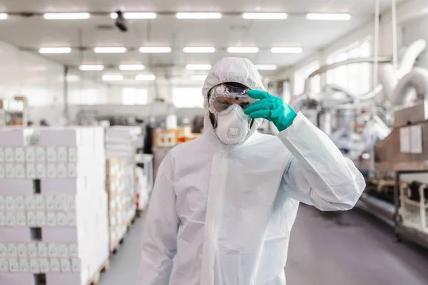 食品工場に立っている間 ガラスを調整するマスクやゴム手袋と保護制服の労働者 — ストック写真