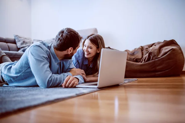 リビングの床に横になって お互いを見ている素敵な白人夫婦の側のビュー 床にはノートパソコンがある — ストック写真