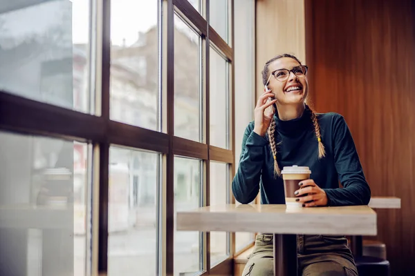 긍정적 여성이 카페테리아에 일회용 커피와 친구와 통화를 — 스톡 사진