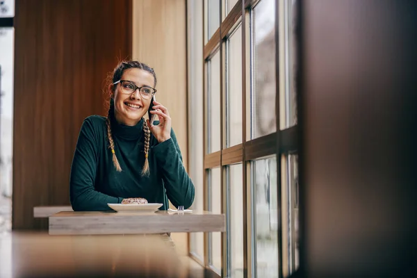 Усміхнена Молода Жінка Сидить Кафетерії Поруч Вікном Розмовляє Телефону Концепція — стокове фото