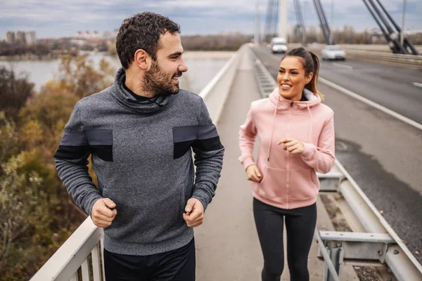 Joven Deportista Guapo Forma Corriendo Por Puente Con Amiga Mirándola — Foto de Stock