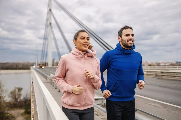 Kendini Bulutlu Bir Havada Köprüde Yan Yana Koşan Sportif Genç — Stok fotoğraf