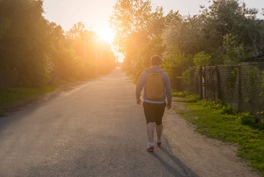 Yaz günbatımı yolda bir sırt çantası ile turist.