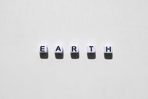 Wort Erde in Würfeln auf weißem Hintergrund an einem sonnigen Tag — Stockfoto