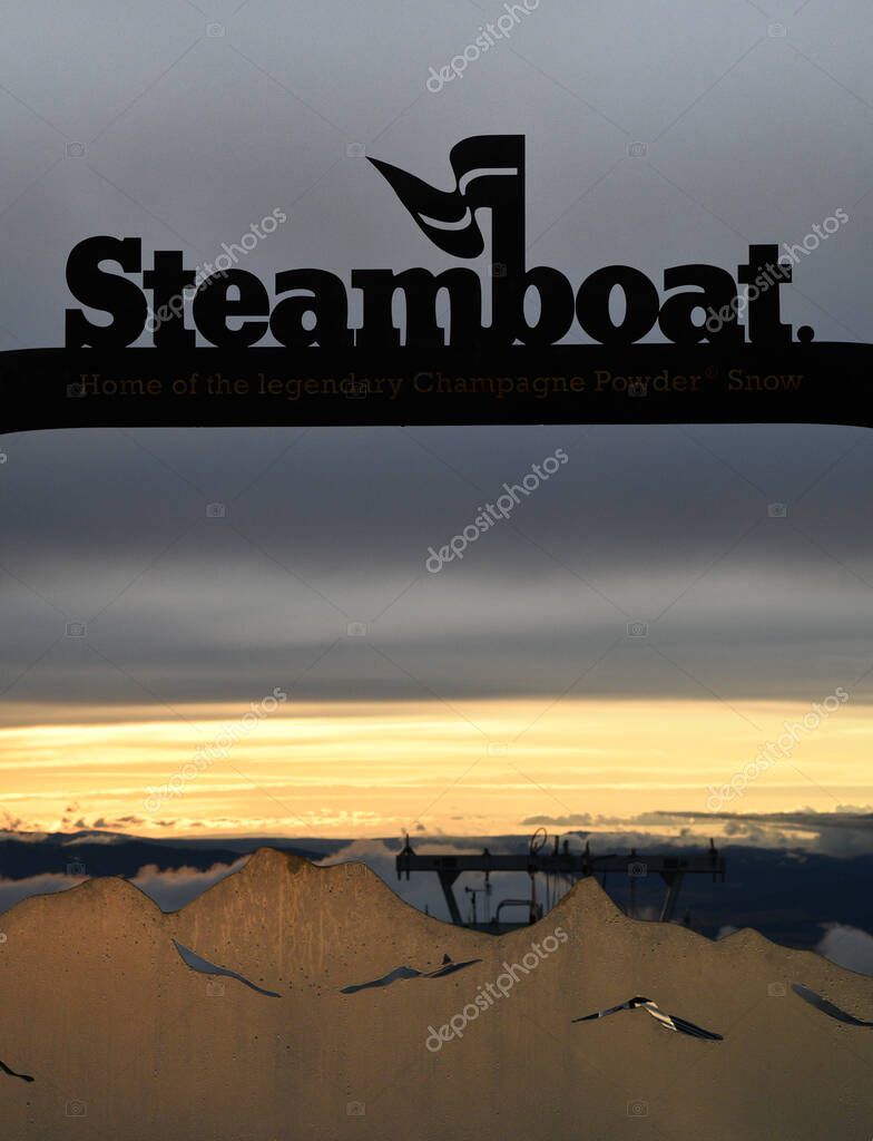 Signage at the mountaintop of ski resort, Steamboat Springs showing a sunset in the background.