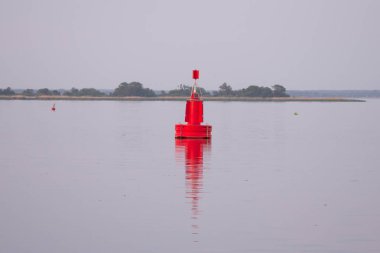 Arka planda kıyı şeridi ile su yansıması ile kırmızı şamandıra