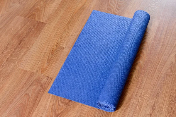 Blue yoga mat on wooden background