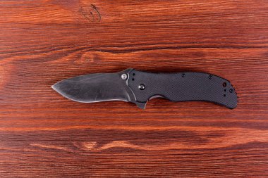 Ahşap artalan üzerinde siyah saplı katlama bıçak