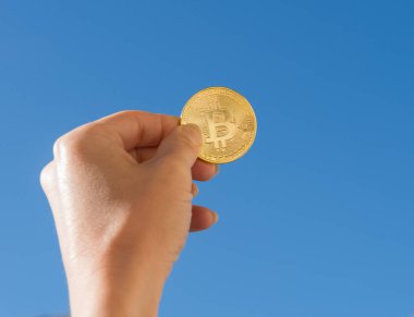 Altın bitcoin sikke mavi gökyüzü arka plan üzerinde tutan el
