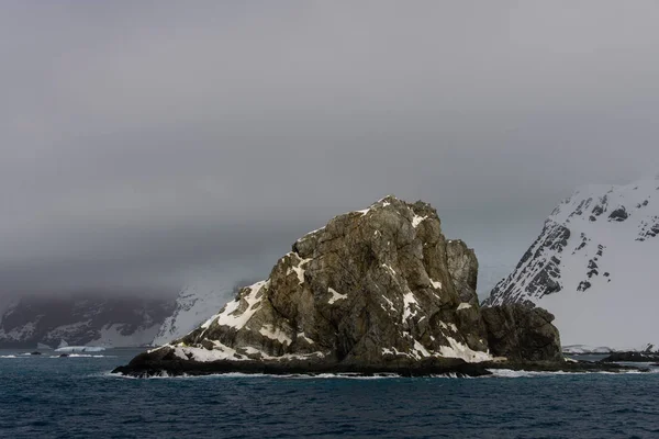 Rock with snow in sea