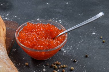 Koyu rustik arka plan üzerinde gümüş kaşık ile cam kavanozda Kırmızı havyar