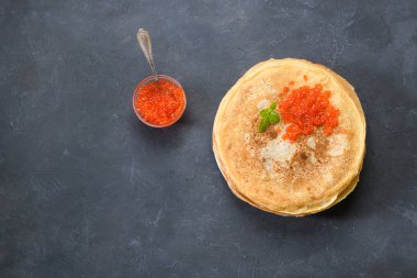 Koyu rustik arka plan üzerinde kırmızı havyar ile krep yığını, boş metin alanı ile üst görünümü