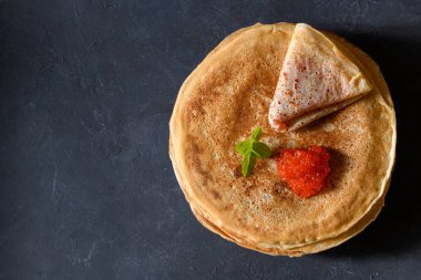 Koyu rustik arka plan üzerinde kırmızı havyar ile krep yığını, boş metin alanı ile üst görünümü