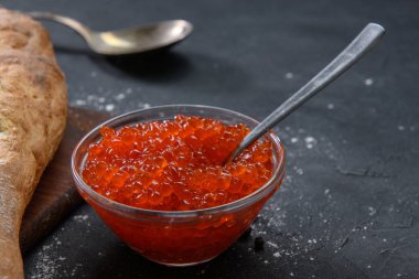 Koyu rustik arka plan üzerinde gümüş kaşık ile cam kavanozda Kırmızı havyar