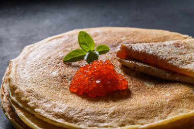 Koyu rustik arka plan üzerinde kırmızı havyar ile krep yığını, yakın