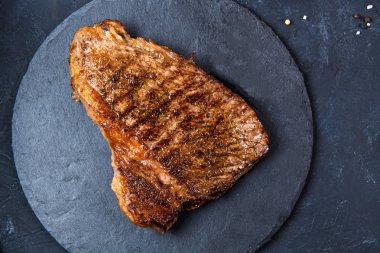 Arka planda az pişmiş ızgara biftek ve pirzola.