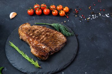 Koyu arkaplanda az pişmiş ızgara biftek.