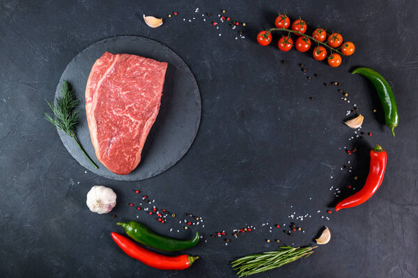 Raw fresh marbled meat and seasonings on dark background top view
