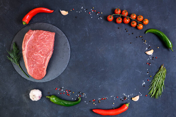 Raw fresh marbled meat and seasonings on dark background top view