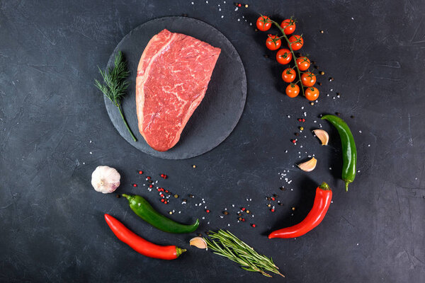 Raw fresh marbled meat and seasonings on dark background top view