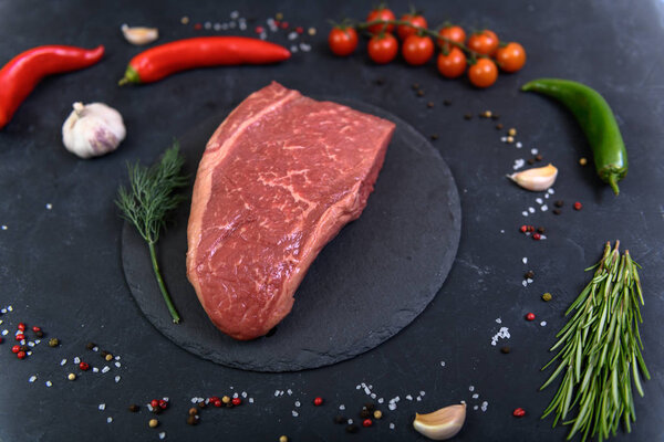 Raw fresh marbled meat and seasonings on dark background top view