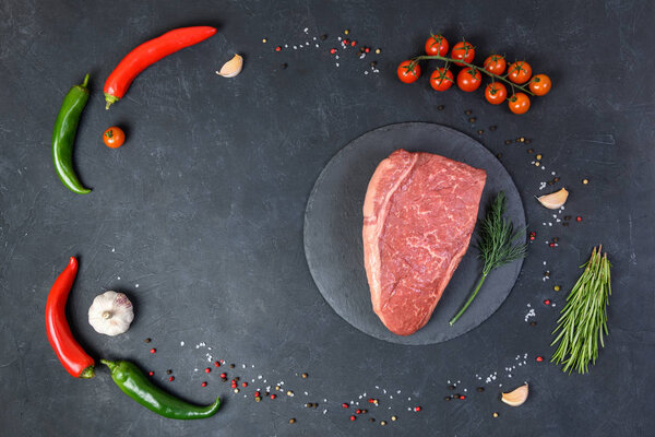 Raw fresh marbled meat and seasonings on dark background top view